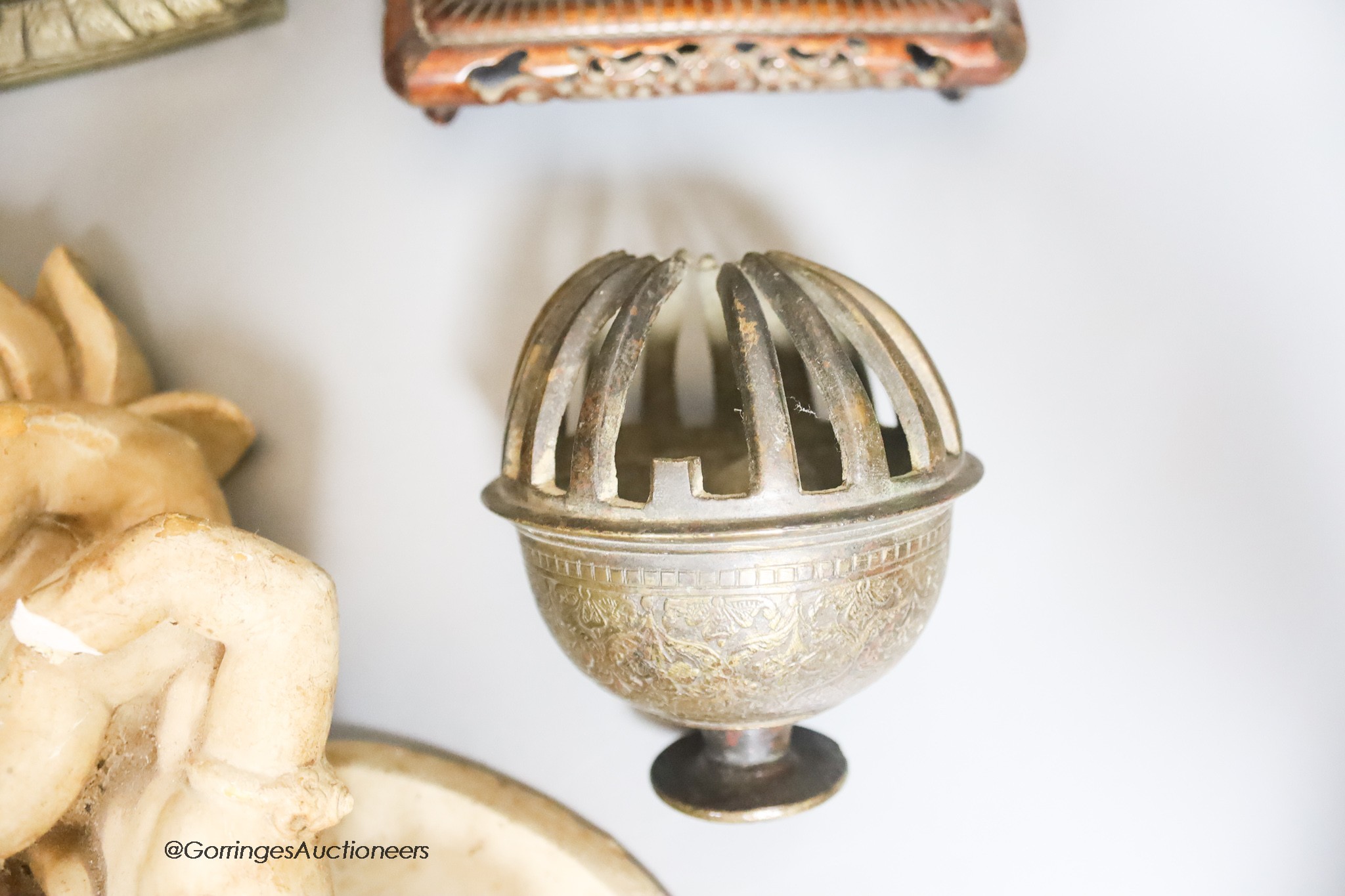 Two reproduction brass figures of Indian deities, a bell, a carved stand and a plaster plaque, tallest 26cm